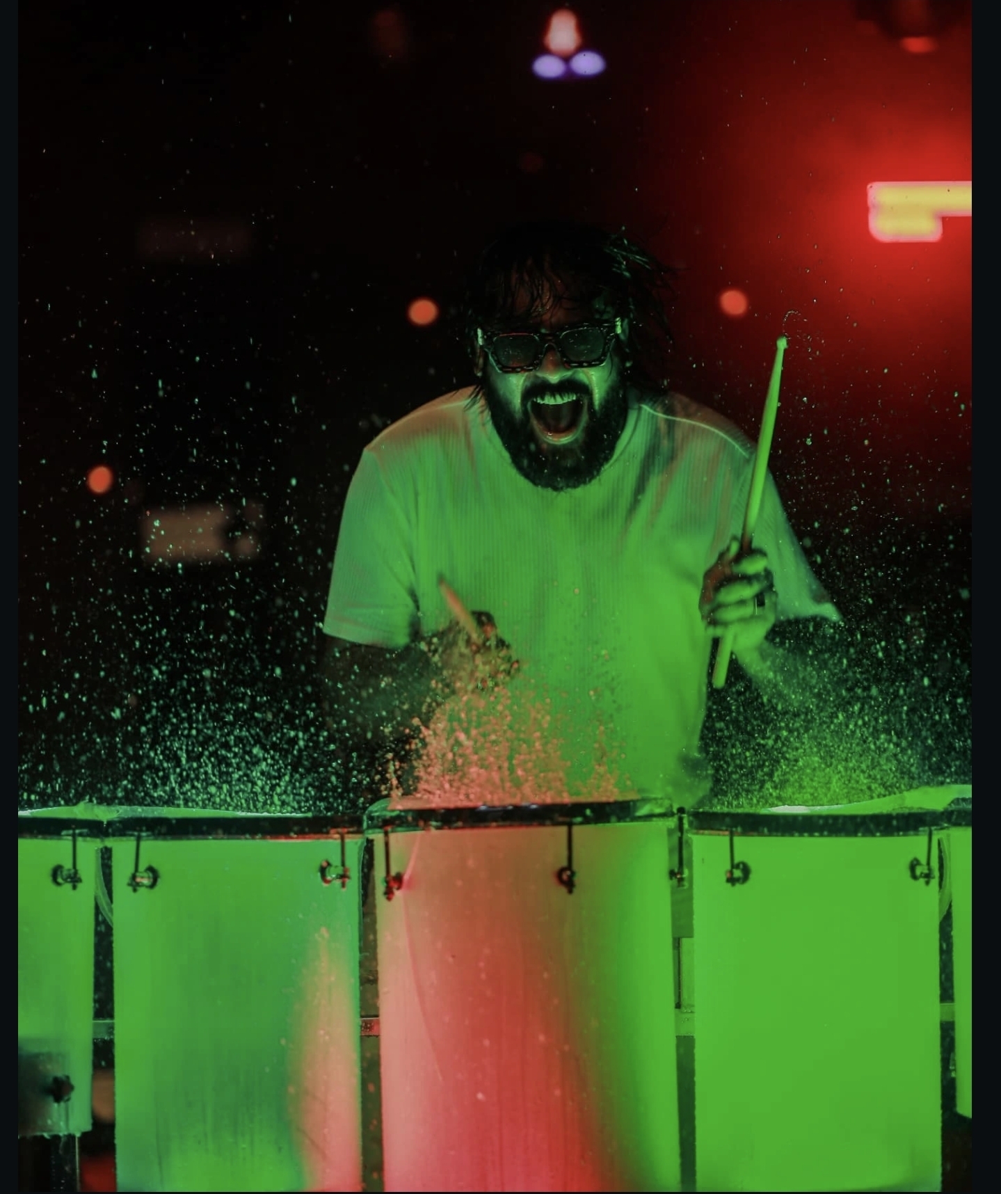 Shiya Majeed performing water drums under green stage light
